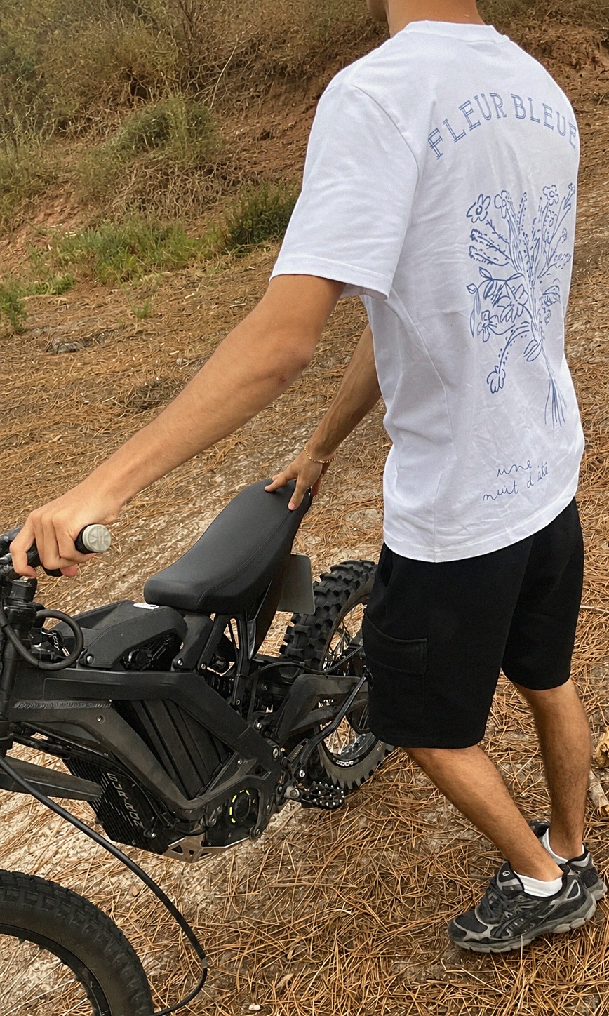 T-shirt Fleur Bleue vu de dos, à côté d'un vélo électrique noir