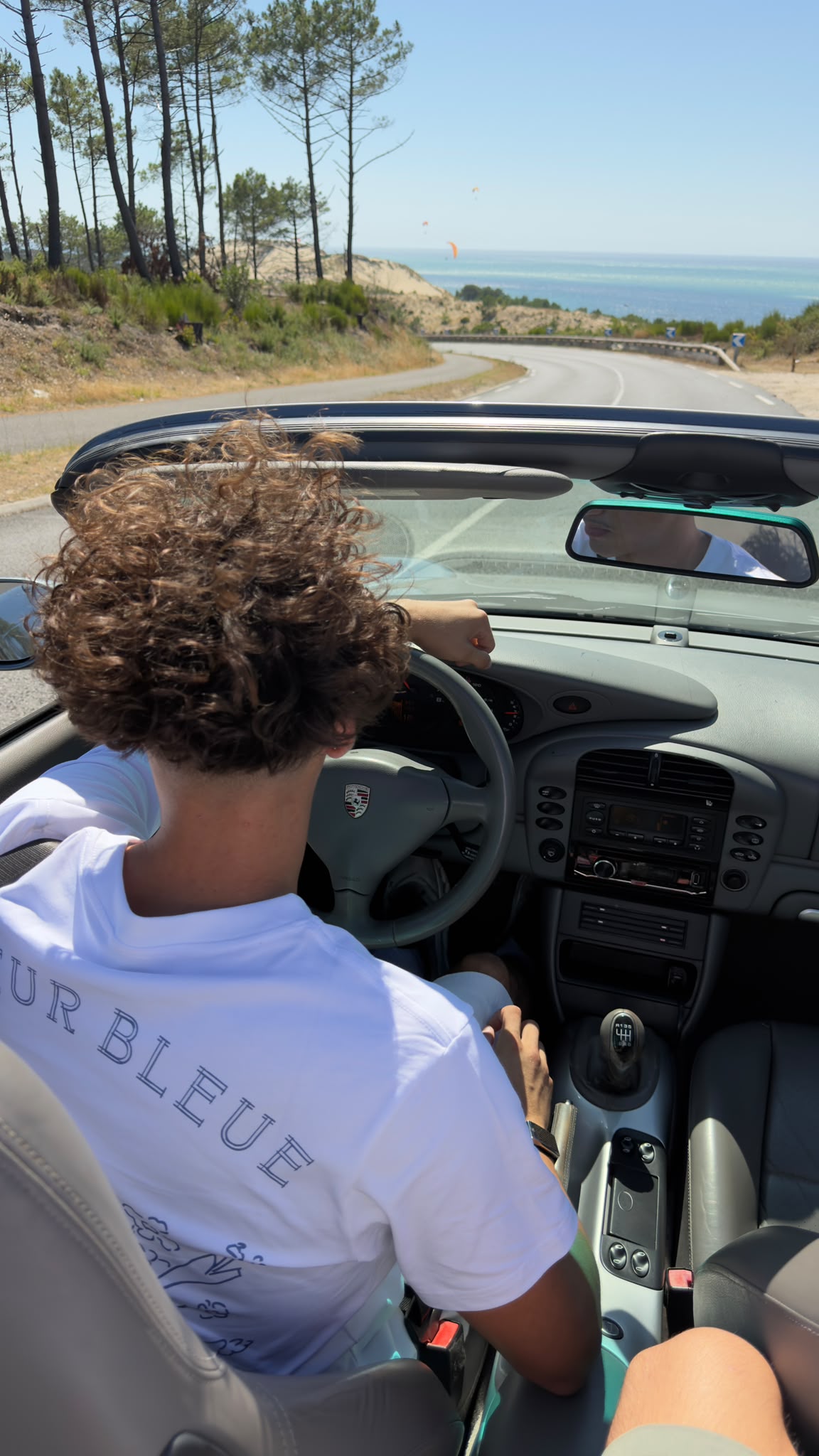 T-shirt Fleur Bleue porté au volant d'une Porsche décapotable